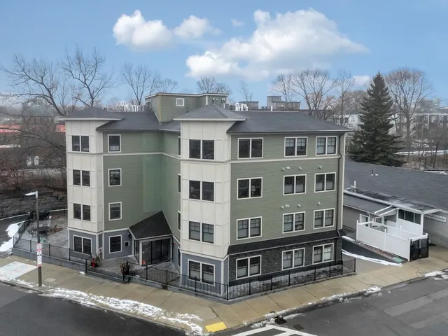 a front view of a building with glass windows and a yard