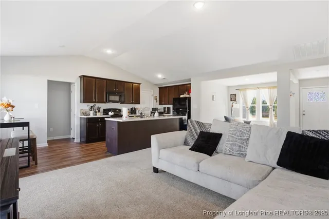 a living room with stainless steel appliances furniture and a view of kitchen