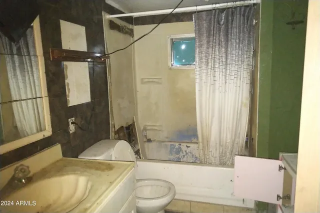 a bathroom with a granite countertop bathtub sink vanity mirror and toilet