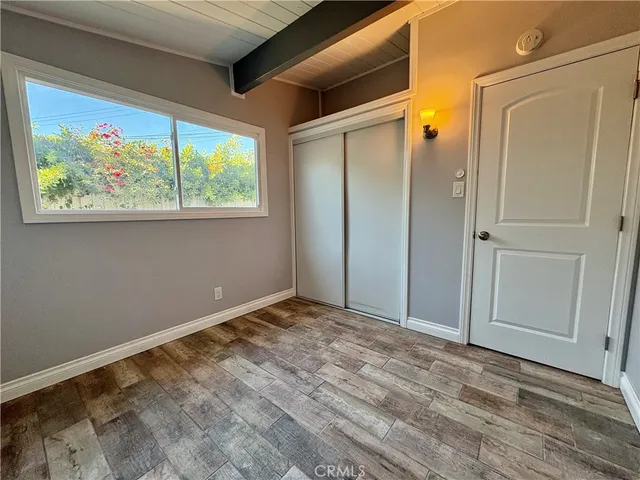 a view of an empty room with wooden floor and window