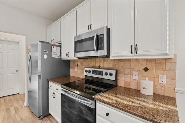 a kitchen with stainless steel appliances granite countertop a stove a microwave and a refrigerator