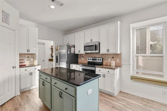 a kitchen with granite countertop a sink a counter space appliances and cabinets