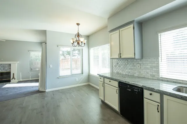 a kitchen with stainless steel appliances granite countertop a sink cabinets a stove and a window