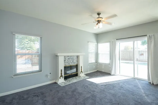 an empty room with windows and ceiling fan