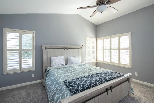 a bedroom with a large bed and two window