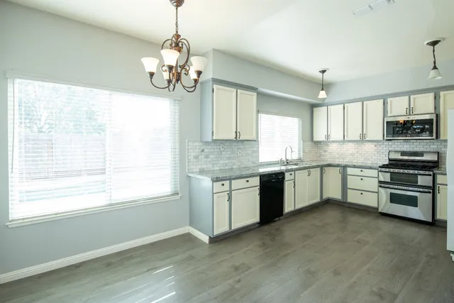 a kitchen with granite countertop stainless steel appliances cabinets a window and a sink