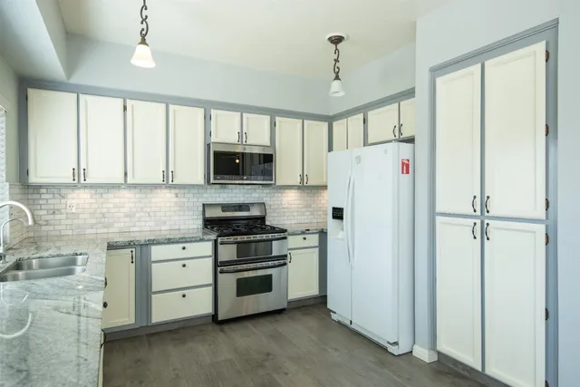 a kitchen with stainless steel appliances a refrigerator sink and white cabinets