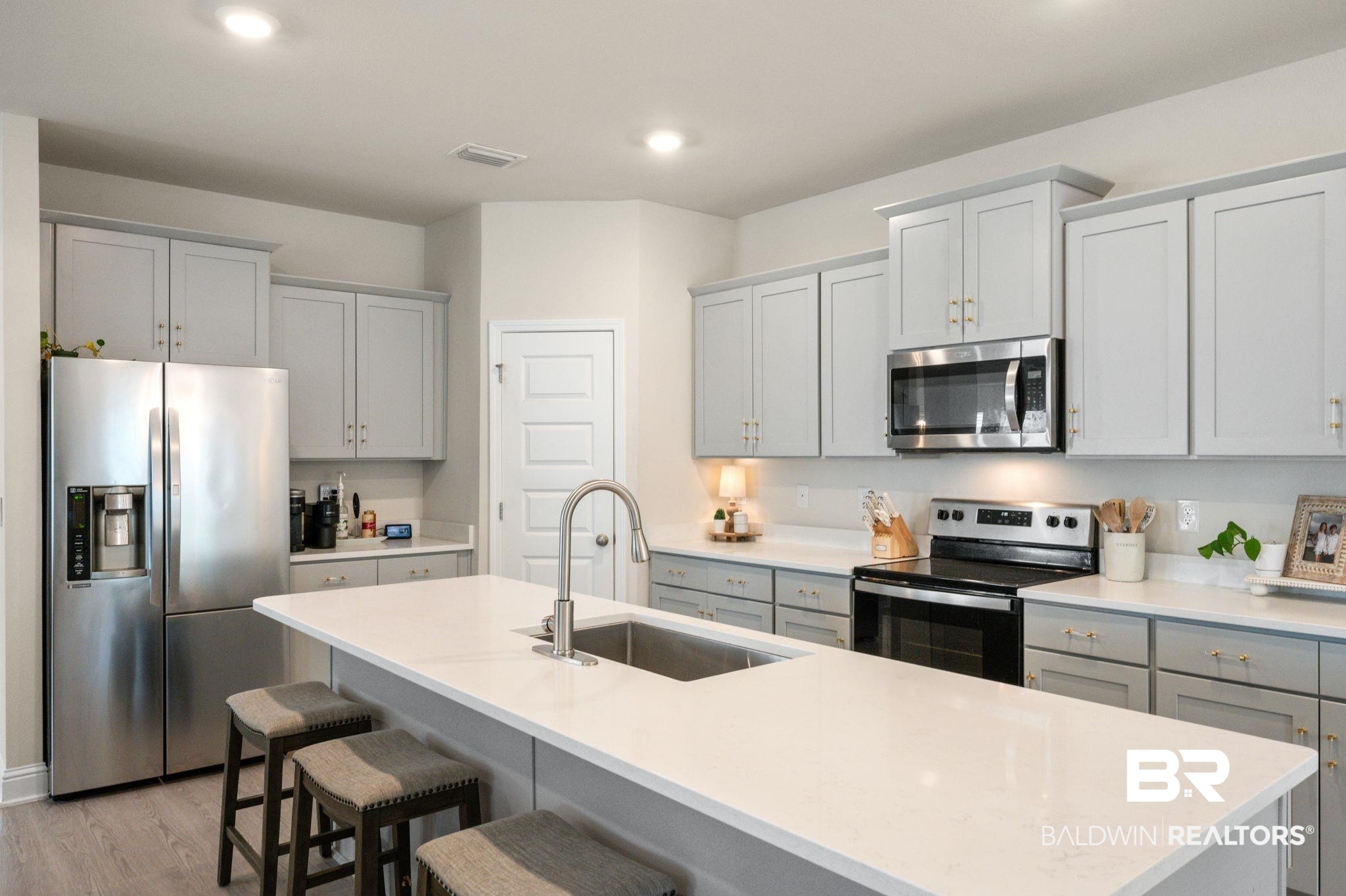 681 Calibre Street Fairhope, AL 36532 - Photo 23 of 56 Kitchen with light wood-type flooring, an island with sink, stainless steel appliances, and sink
