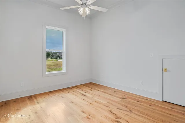 an empty room with wooden floor cabinet and windows
