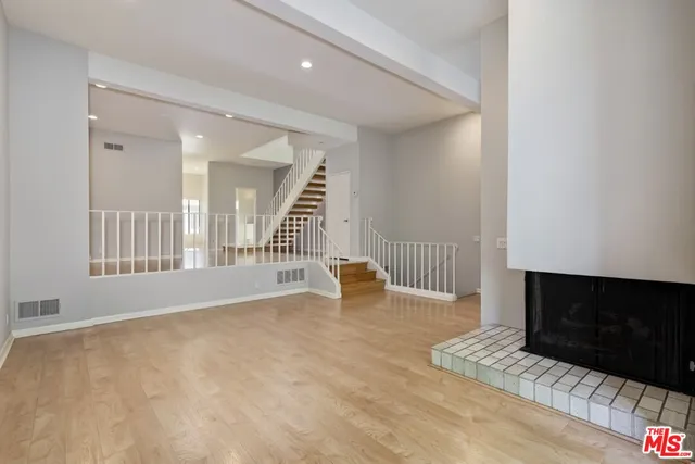 a view of an empty room with stairs and a fireplace