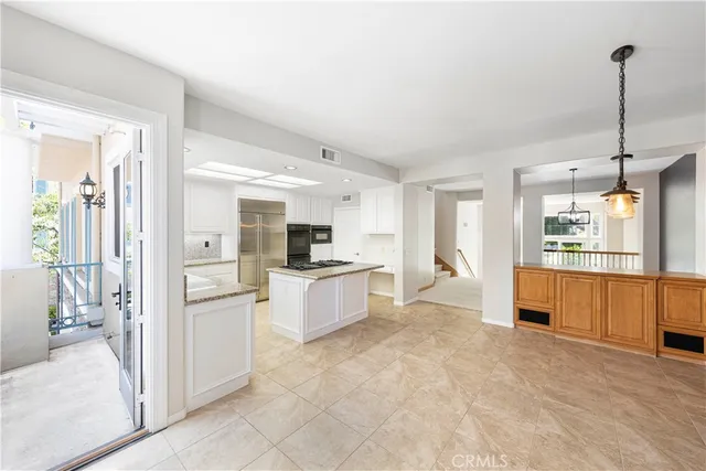 a large kitchen with kitchen island a refrigerator a sink dishwasher with a stove and white cabinets