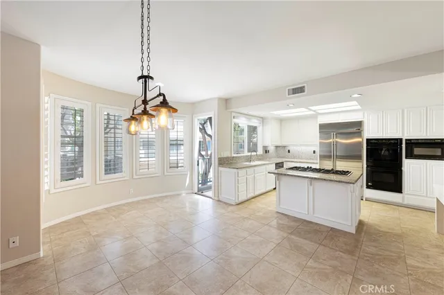 a large white kitchen with granite countertop a stove a sink a window and stainless steel appliances