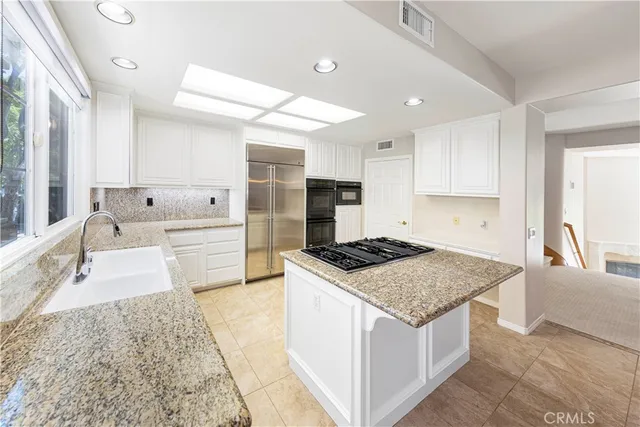 a kitchen with stainless steel appliances granite countertop a stove a sink and a refrigerator