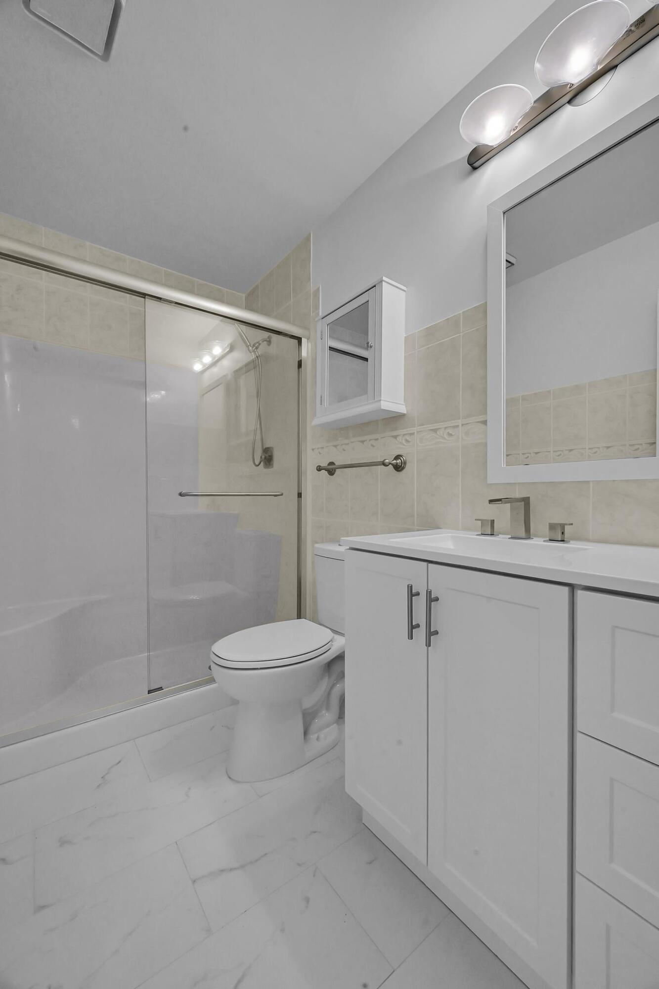 2 Lake Vista Trail, Unit 107 Port St. Lucie, FL 34952 - Photo 17 of 19 a bathroom with a shower sink vanity and toilet