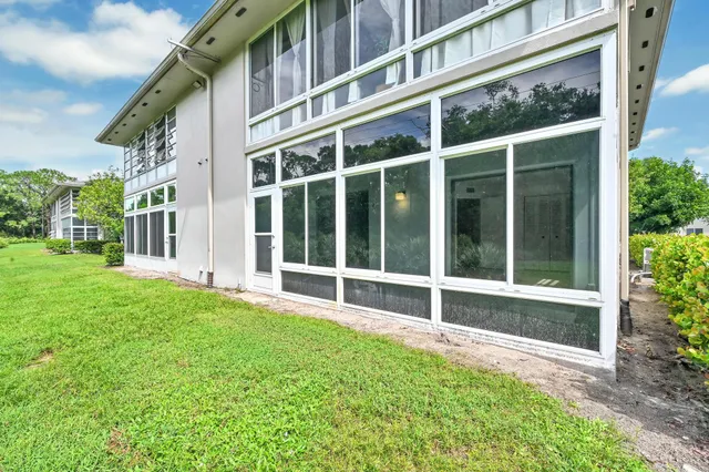 a view of a house with a large window and a yard with wooden fence