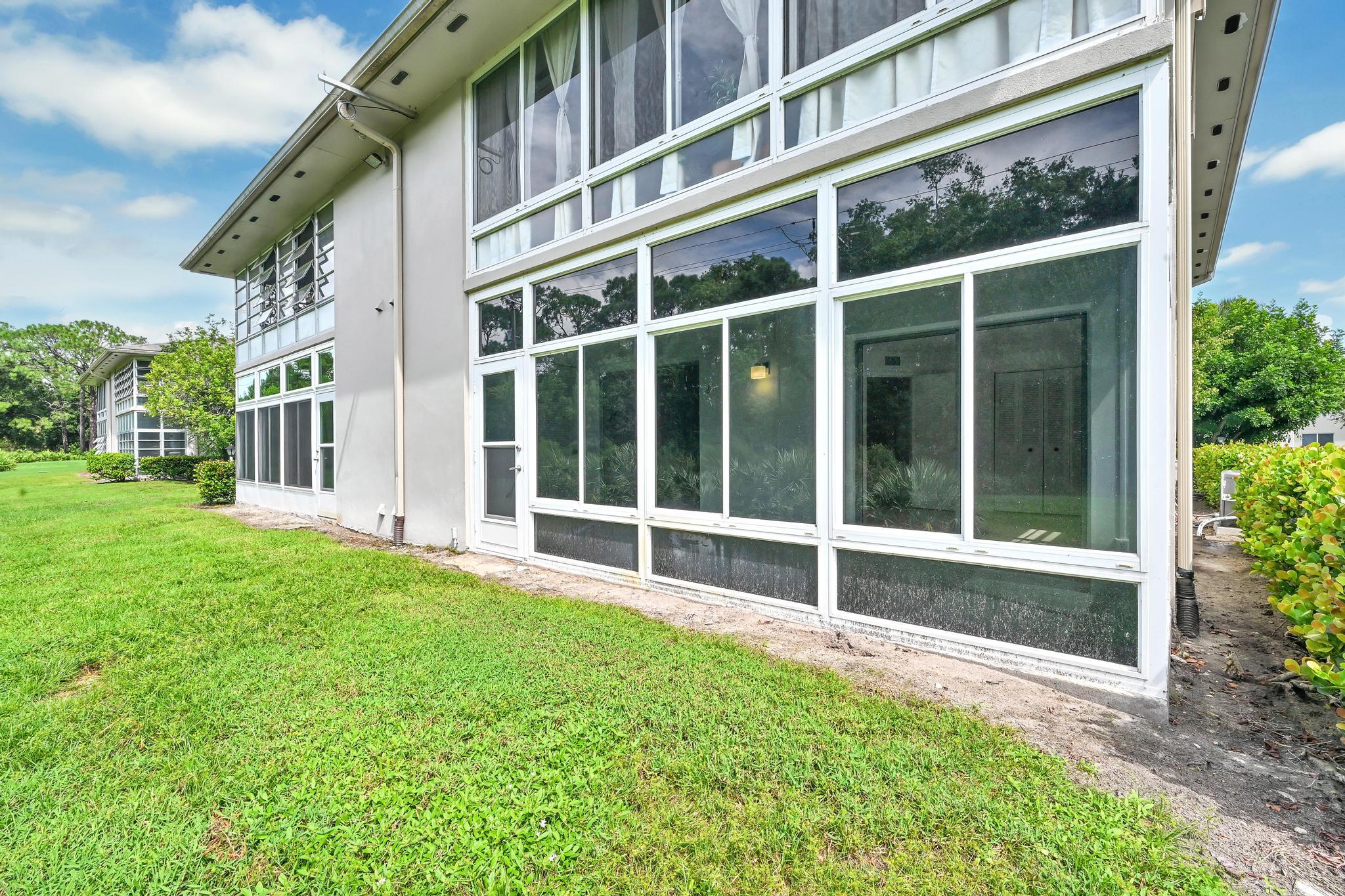 2 Lake Vista Trail, Unit 107 Port St. Lucie, FL 34952 - Photo 2 of 19 a view of a house with a large window and a yard with wooden fence