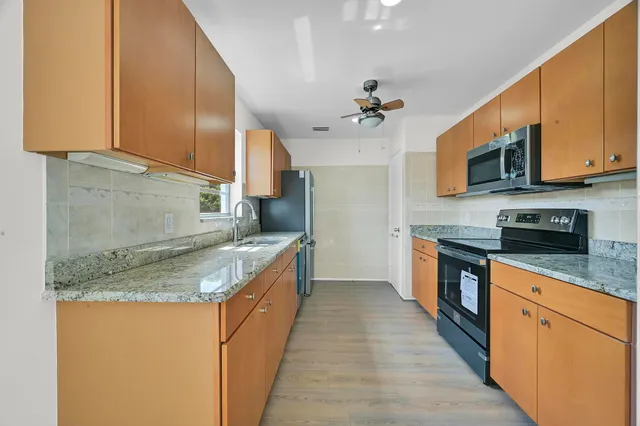 a kitchen with stainless steel appliances granite countertop a sink dishwasher stove top oven and cabinets with wooden floor