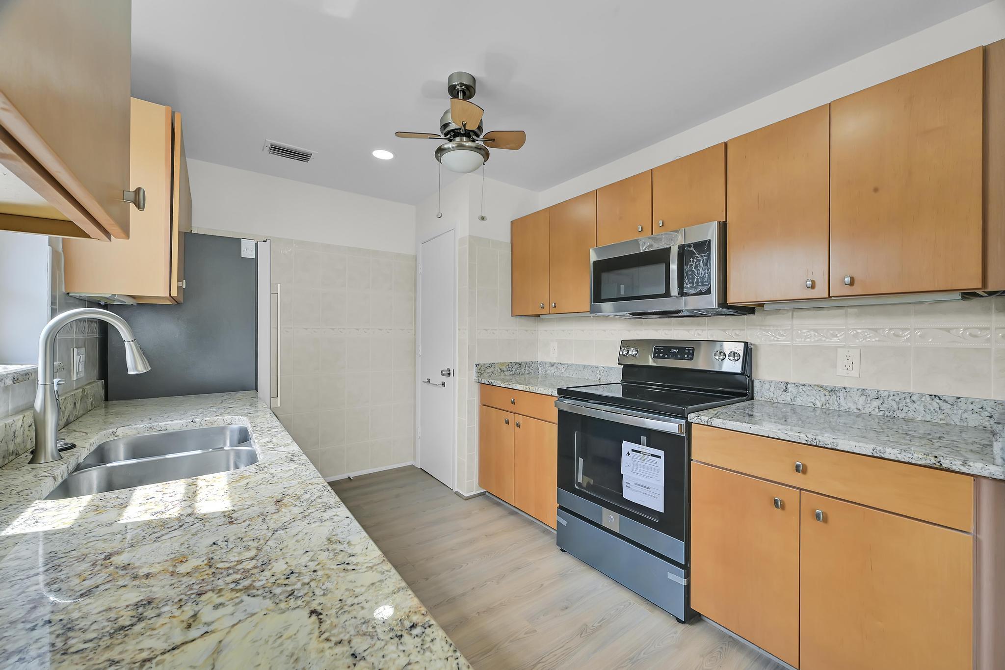 2 Lake Vista Trail, Unit 107 Port St. Lucie, FL 34952 - Photo 7 of 19 a kitchen with stainless steel appliances granite countertop a sink dishwasher stove top oven and cabinets with wooden floor