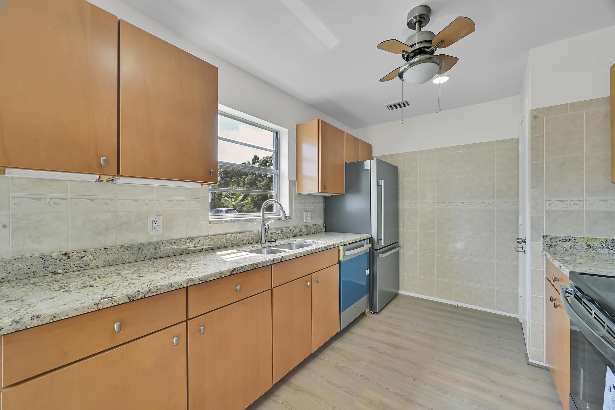 2 Lake Vista Trail, Unit 107 Port St. Lucie, FL 34952 - Photo 8 of 19 a kitchen with stainless steel appliances granite countertop a sink a stove and a refrigerator