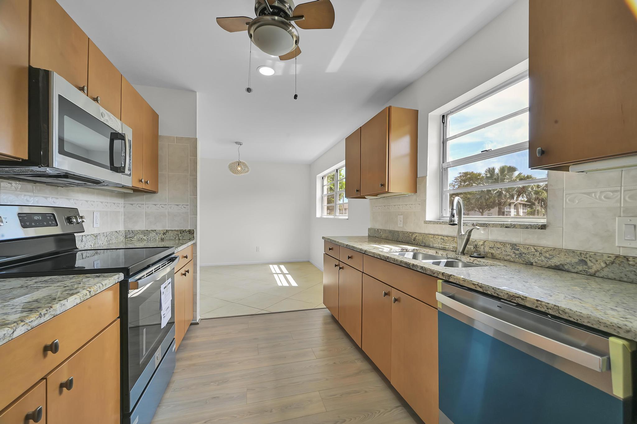 2 Lake Vista Trail, Unit 107 Port St. Lucie, FL 34952 - Photo 9 of 19 a kitchen with stainless steel appliances granite countertop a sink a stove top oven a counter space and cabinets