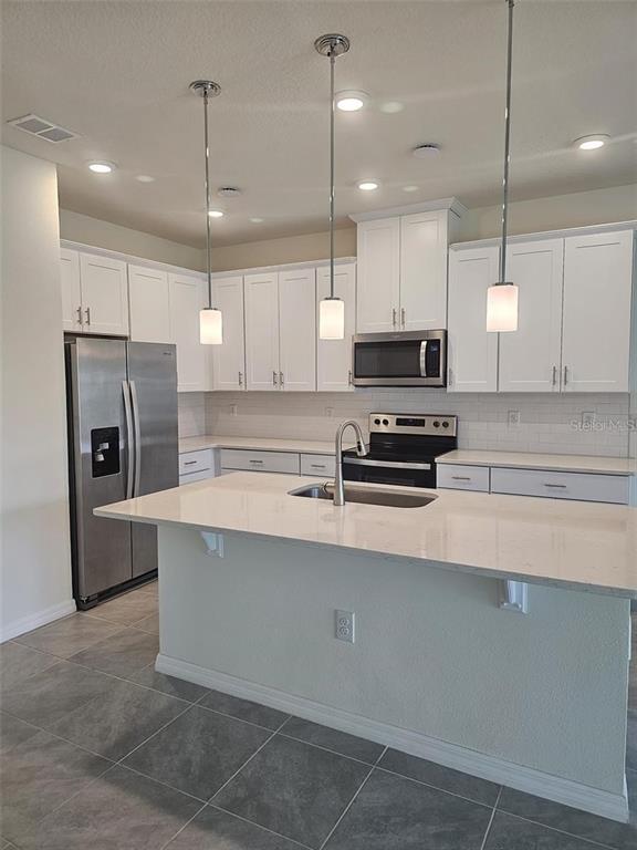 4389 Small Creek Road Kissimmee, FL 34744 - Photo 2 of 17 a kitchen with stainless steel appliances a stove a sink a microwave a center island and cabinets