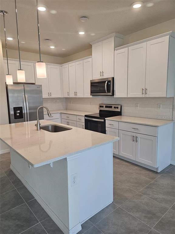 4389 Small Creek Road Kissimmee, FL 34744 - Photo 3 of 17 a kitchen with kitchen island a sink a stove and cabinets