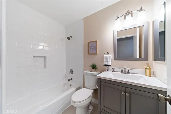 a bathroom with a toilet a sink a mirror a bathtub and vanity