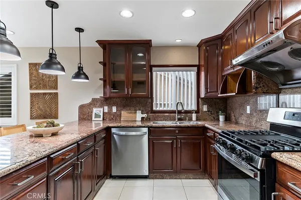 a kitchen with stainless steel appliances granite countertop a sink a stove and a wooden floors