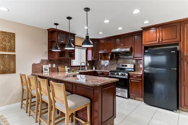a kitchen with stainless steel appliances granite countertop a sink a stove a refrigerator cabinets and a dining table