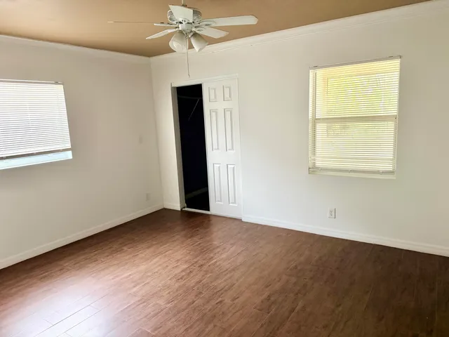 an empty room with wooden floor closet and windows