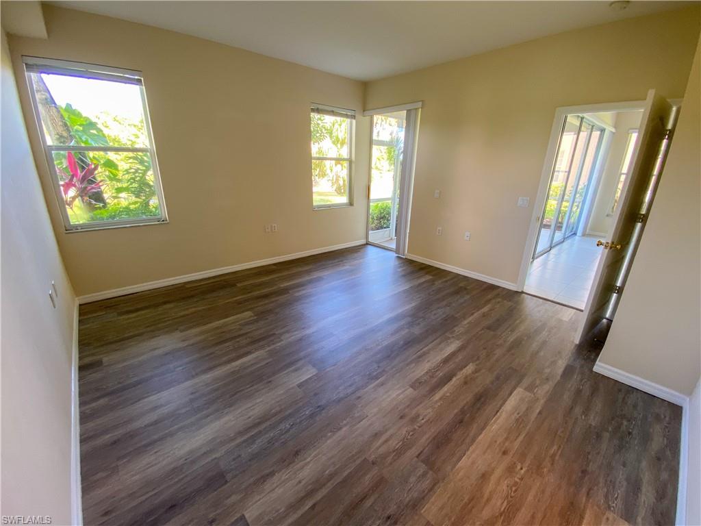 1993 Crestview Way, Unit 129 Naples, FL 34119 - Photo 13 of 26 a view of an empty room with wooden floor and a window