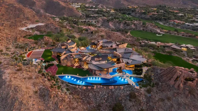 an aerial view of a house with a swimming pool and mountains