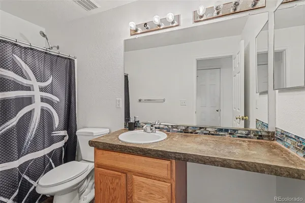 a bathroom with a granite countertop sink a toilet a mirror and shower
