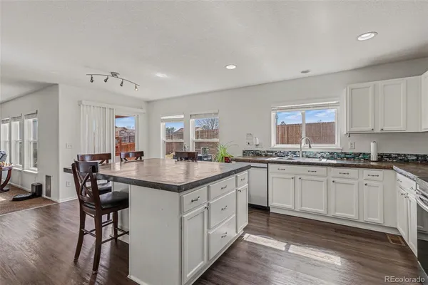 a kitchen with granite countertop white cabinets and chairs