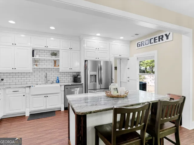 a kitchen with stainless steel appliances granite countertop a kitchen island hardwood floor and a sink