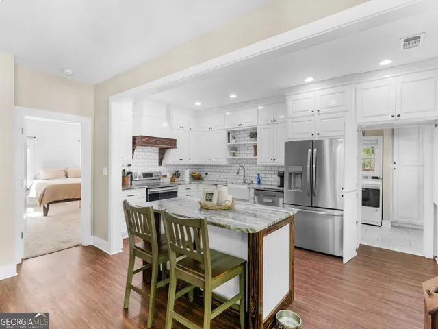 a kitchen with stainless steel appliances granite countertop a dining table chairs refrigerator and microwave