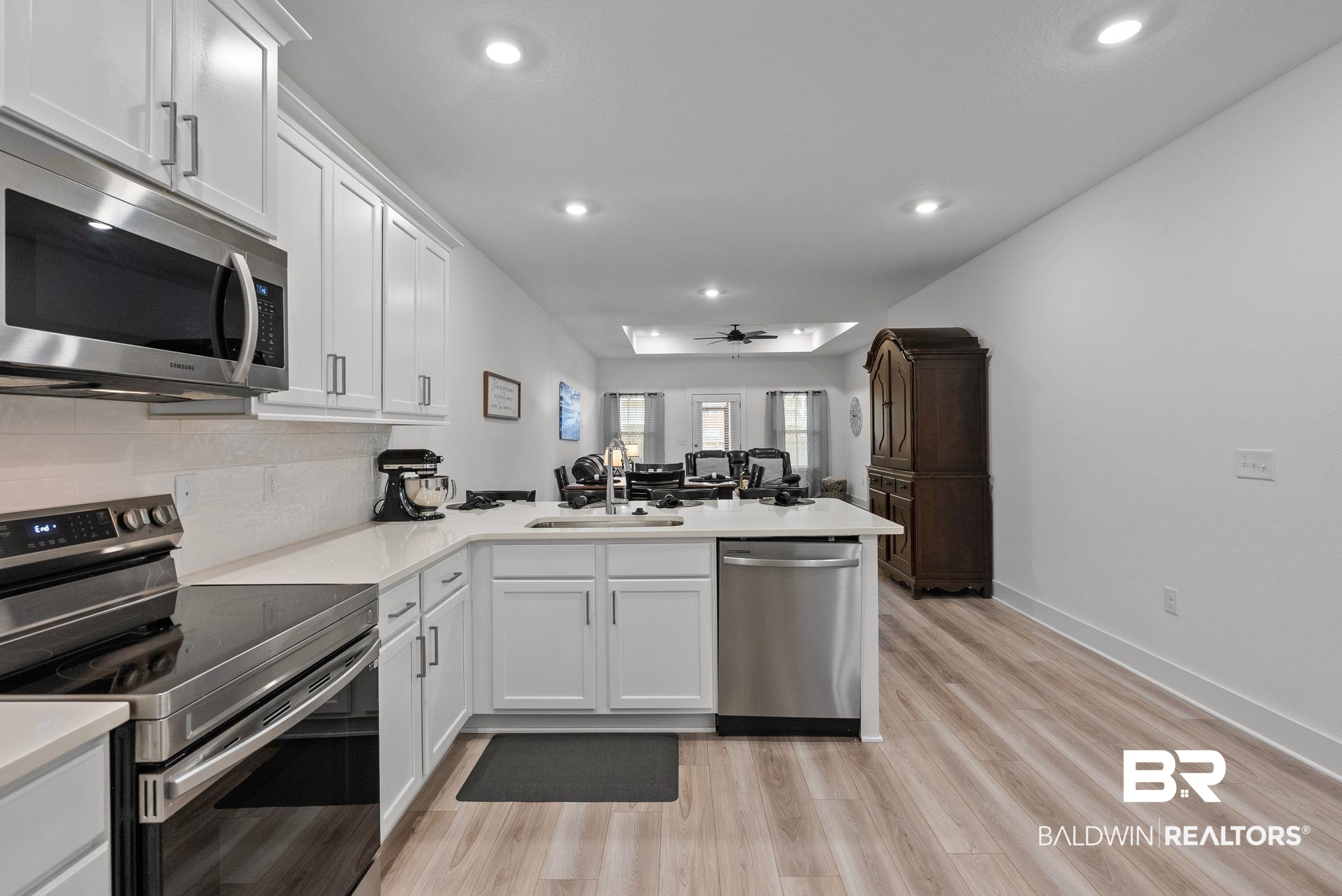 9899 Willet Way Foley, AL 36535 - Photo 13 of 37 Modern kitchen featuring white shaker cabinetry, stainless steel appliances, light-toned countertops, and wood-finish flooring