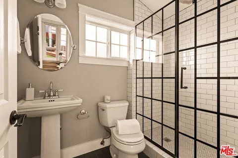 a bathroom with a sink mirror toilet and next to a window