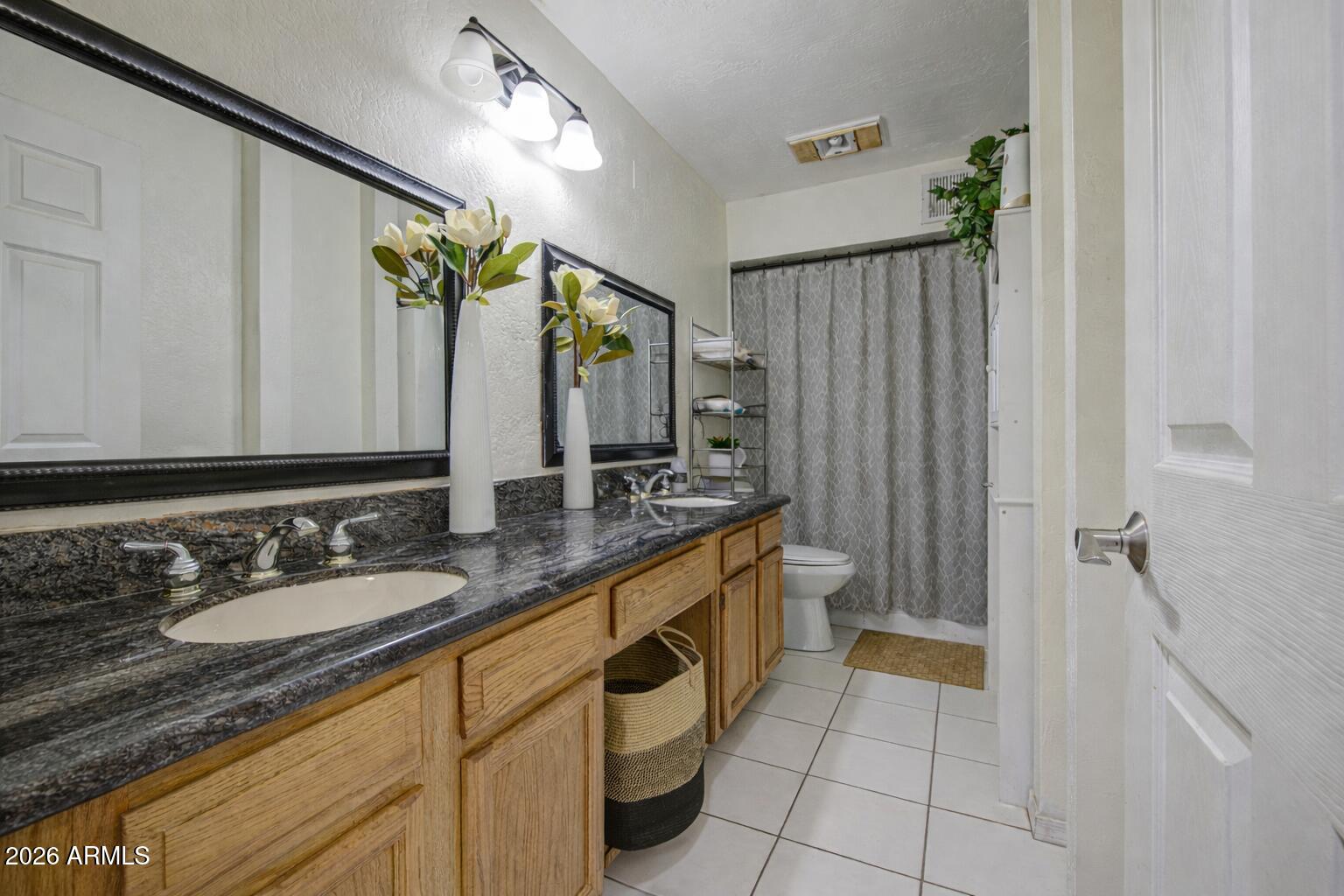 3107 West Montebello Avenue Phoenix, AZ 85017 - Photo 18 of 30 a spacious bathroom with a granite countertop sink and a mirror