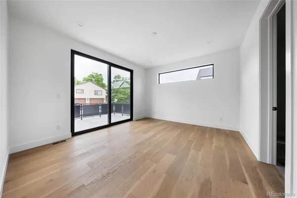 a view of a hallway with wooden floor and a bathroom