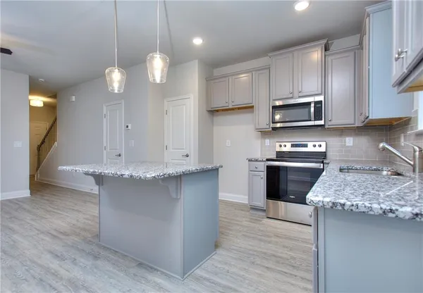 a kitchen with kitchen island granite countertop a stove a sink a refrigerator and a wooden cabinets