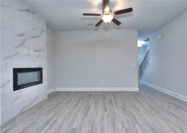 an empty room with wooden floor a ceiling fan and fireplace