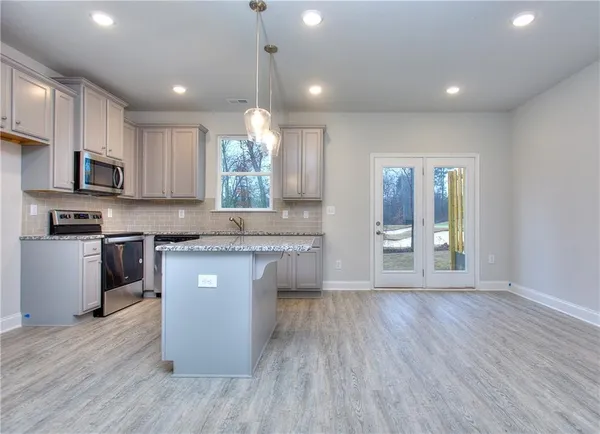 a kitchen with stainless steel appliances granite countertop wooden cabinets a refrigerator a sink a stove a microwave and wooden floors