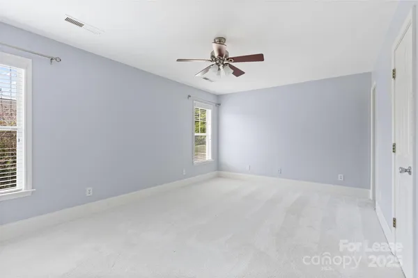 an empty room with windows and fan