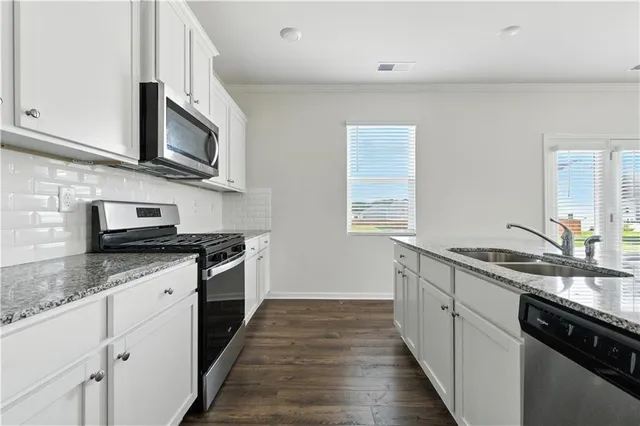 a kitchen with stainless steel appliances granite countertop a sink stove and microwave