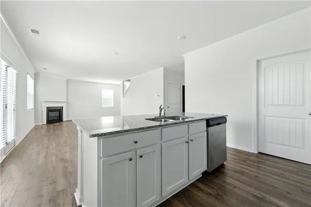 a kitchen with granite countertop a sink and dishwasher with wooden floor