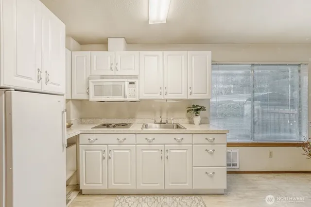 a kitchen with granite countertop white cabinets and white appliances