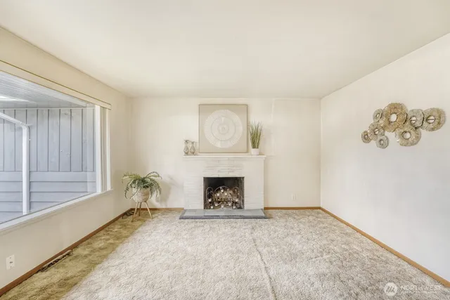 an empty room with windows and fireplace