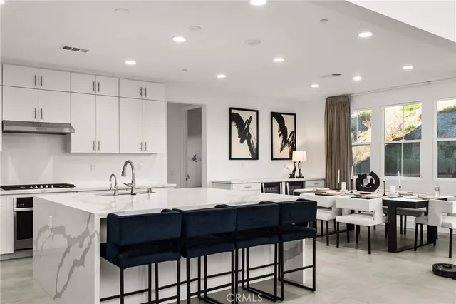 a kitchen with a dining table chairs sink and white cabinets