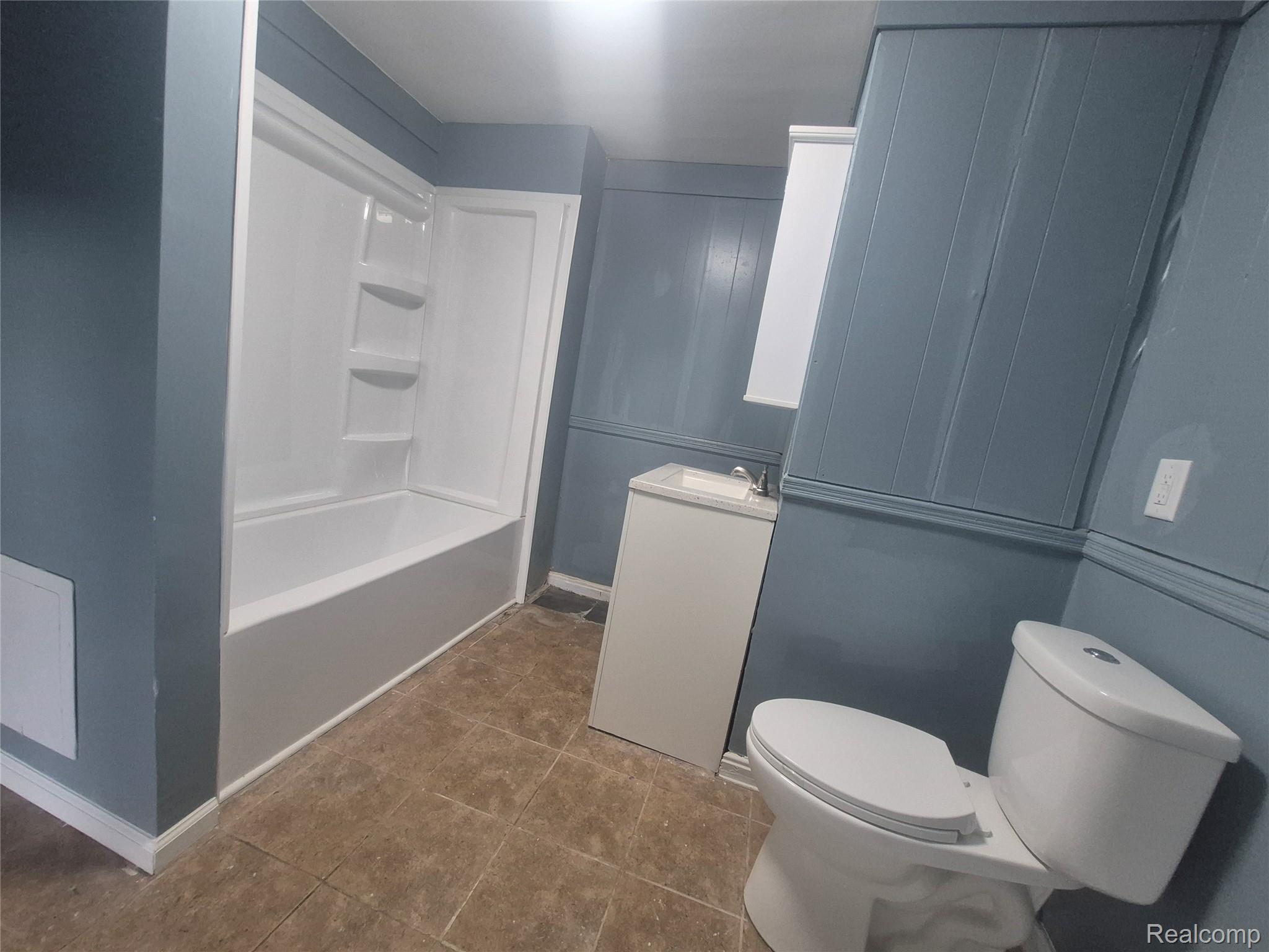 16758 Frazho Road Roseville, MI 48066 - Photo 16 of 53 Tub/shower combination with integrated shelving, single vanity with countertop, wall-mounted mirror, and tile flooring